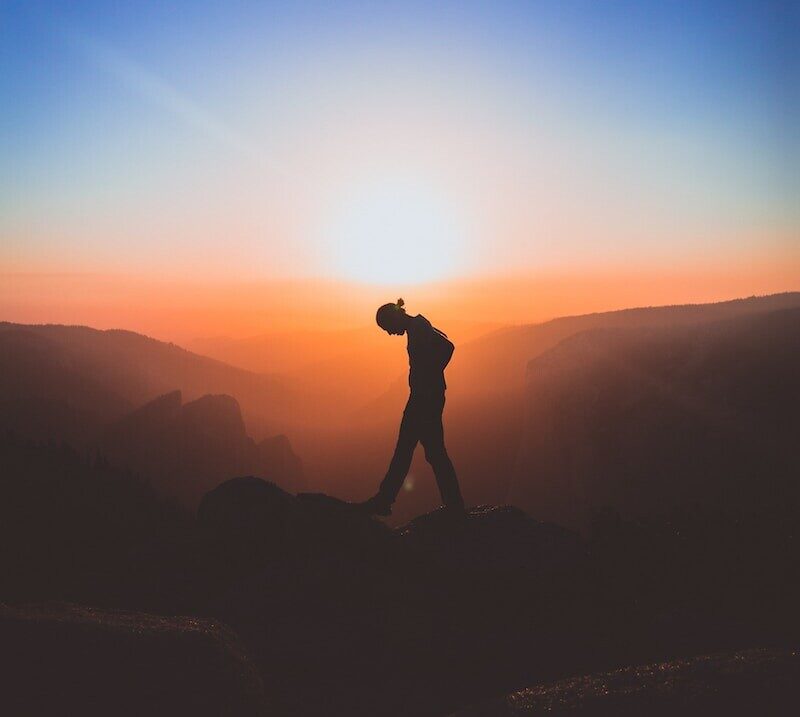 silhouette of man standing on mountain peak
